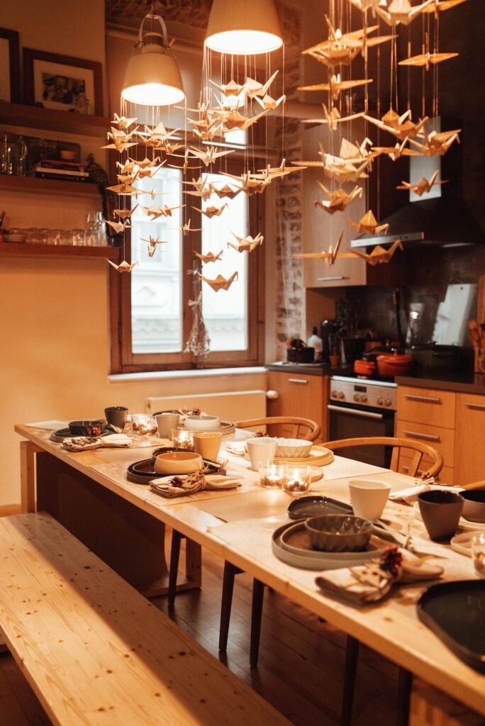 pexels-photo-6310295-6310295 Warm and inviting kitchen with elegant origami crane decor above a rustic wooden table setting.